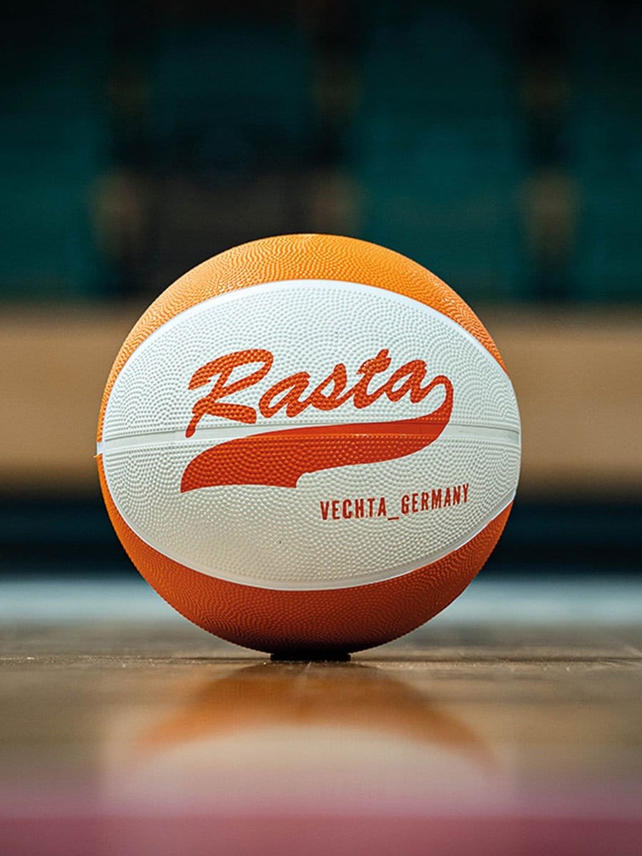 Basketball mit weißer und oranger Oberfläche, auf der "Basta" und "Vechta_Germany" in roter Schrift steht, liegt auf einem Basketballfeld.