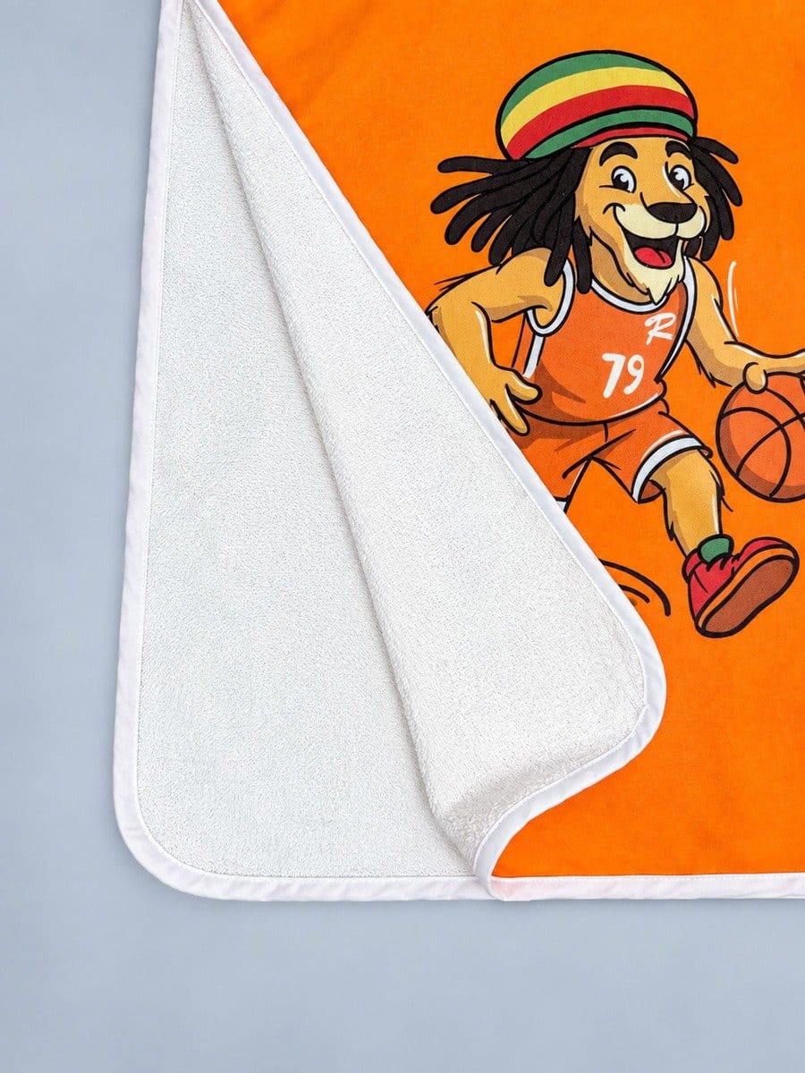 Frottee-Handtuch mit buntem Löwen-Design, das einen Basketball spielt, auf orangefarbenem Hintergrund, mit weißem Rand, halb gefaltet.