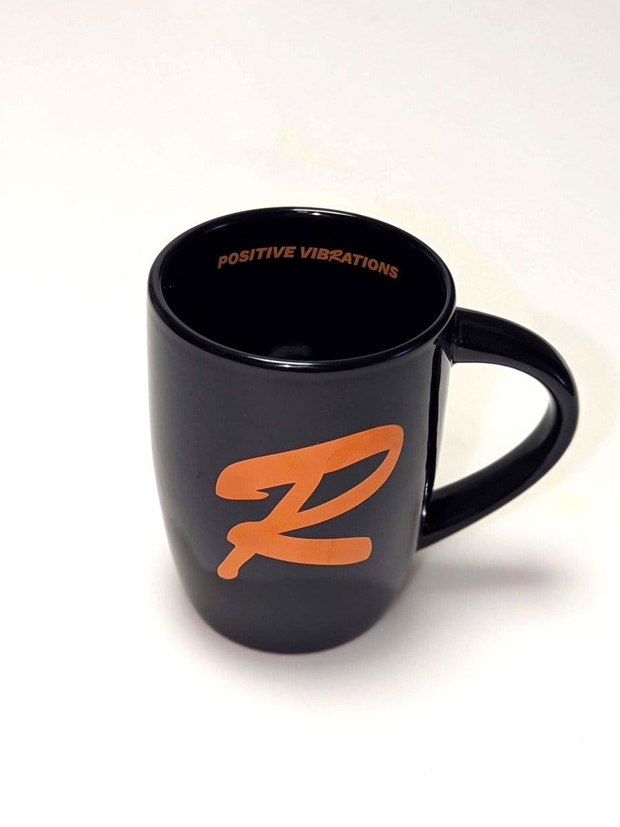 Schwarze Tasse mit orangefarbenem Z-Logo und dem Schriftzug "POSITIVE VIBRATIONS" im Inneren, auf weißem Hintergrund.